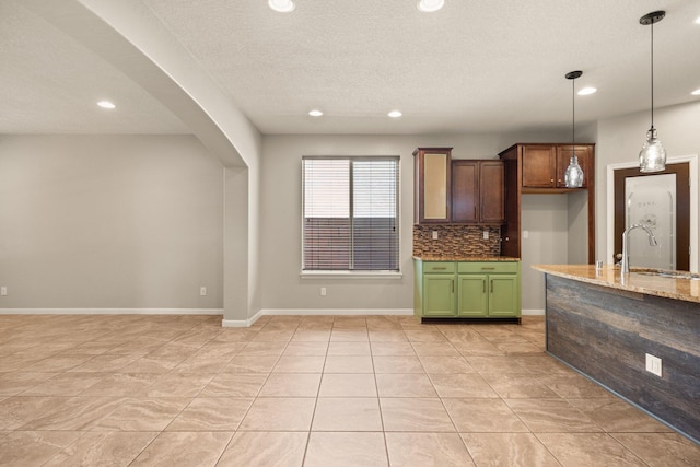 4909 Calle Espana NW, Albuquerque, NM 87120 - kitchen with a sink, green cabinetry, tasteful backsplash, recessed lighting, and light stone counters