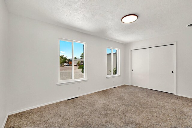 357 Meade Ct, Rio Communities, NM 87002 - unfurnished bedroom featuring carpet flooring, a textured ceiling, baseboards, and a closet