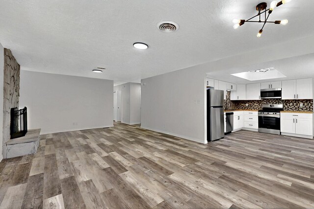 357 Meade Ct, Rio Communities, NM 87002 - unfurnished living room with light wood-type flooring, a chandelier, a textured ceiling, and baseboards