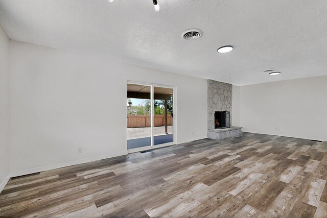 357 Meade Ct, Rio Communities, NM 87002 - unfurnished living room featuring wood finished floors, a textured ceiling, a stone fireplace, and baseboards