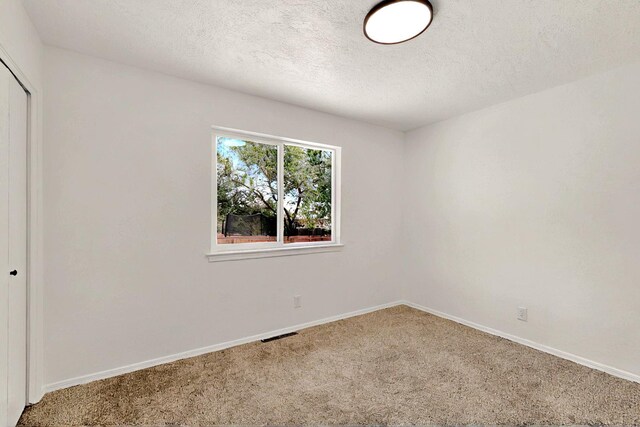 357 Meade Ct, Rio Communities, NM 87002 - unfurnished bedroom featuring carpet flooring, a closet, a textured ceiling, and baseboards