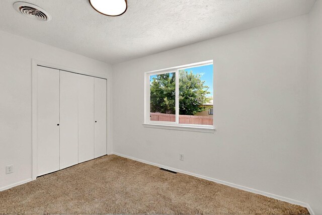 357 Meade Ct, Rio Communities, NM 87002 - unfurnished bedroom with carpet floors, baseboards, a closet, and a textured ceiling