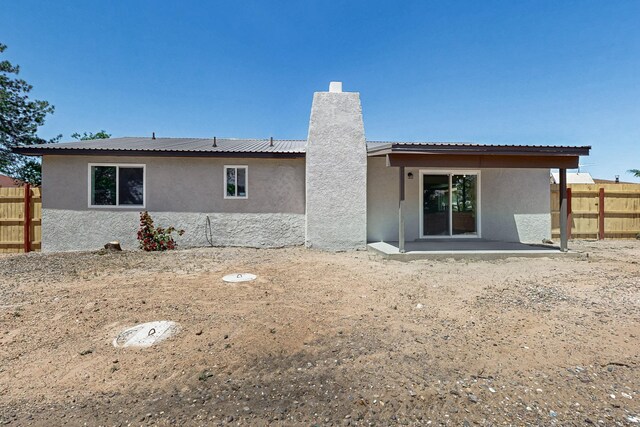 357 Meade Ct, Rio Communities, NM 87002 - rear view of property featuring stucco siding, fence, a patio, a chimney, and metal roof