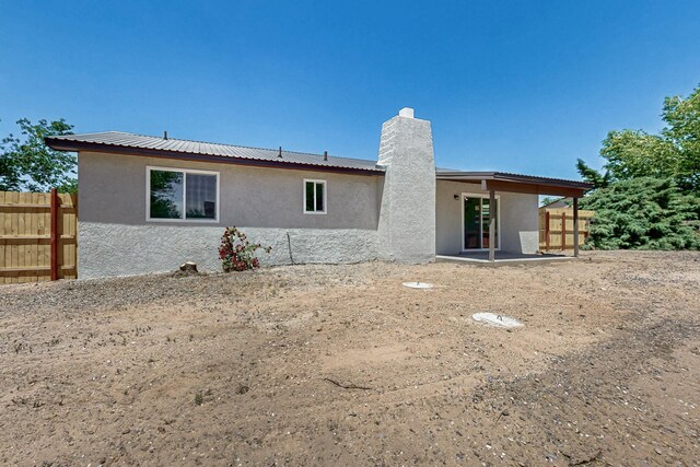 357 Meade Ct, Rio Communities, NM 87002 - rear view of house featuring stucco siding, a chimney, fence, and metal roof