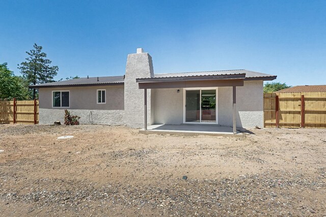 357 Meade Ct, Rio Communities, NM 87002 - back of house with stucco siding, a chimney, a fenced backyard, a patio, and metal roof