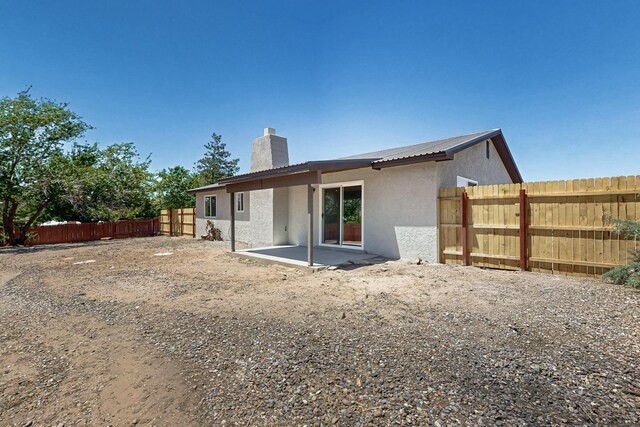 357 Meade Ct, Rio Communities, NM 87002 - back of house with stucco siding, a chimney, a fenced backyard, and a patio area