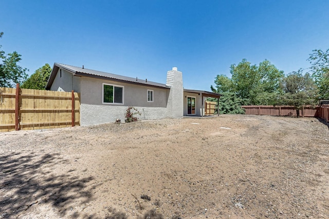 357 Meade Ct, Rio Communities, NM 87002 - back of property featuring stucco siding, a fenced backyard, a chimney, and metal roof
