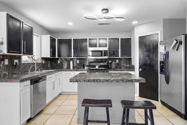 656 Cottontail St SW, Albuquerque, NM 87121 - kitchen with stainless steel appliances, a sink, backsplash, light tile patterned floors, and dark countertops