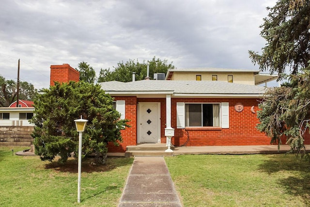 2701 Chapulin Rd SW, Albuquerque, NM 87105 - view of front facade with a chimney, a front yard, and brick siding