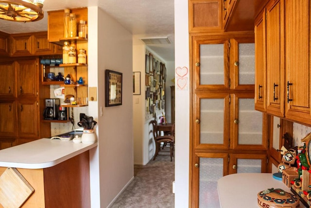 2701 Chapulin Rd SW, Albuquerque, NM 87105 - kitchen featuring brown cabinets, a peninsula, light countertops, glass insert cabinets, and carpet floors