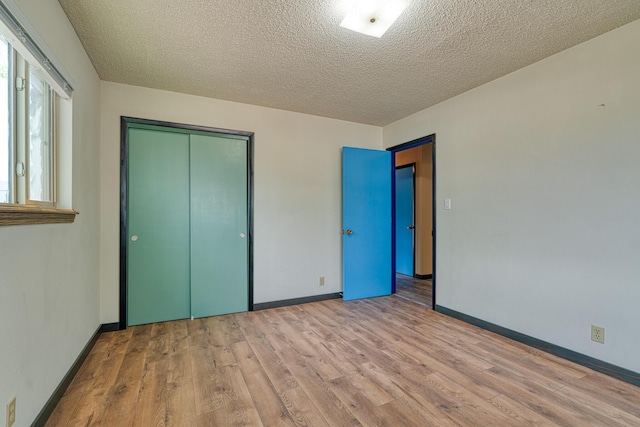 508 Las Marias Dr SE, Rio Rancho, NM 87124 - unfurnished bedroom with wood finished floors, baseboards, a closet, and a textured ceiling