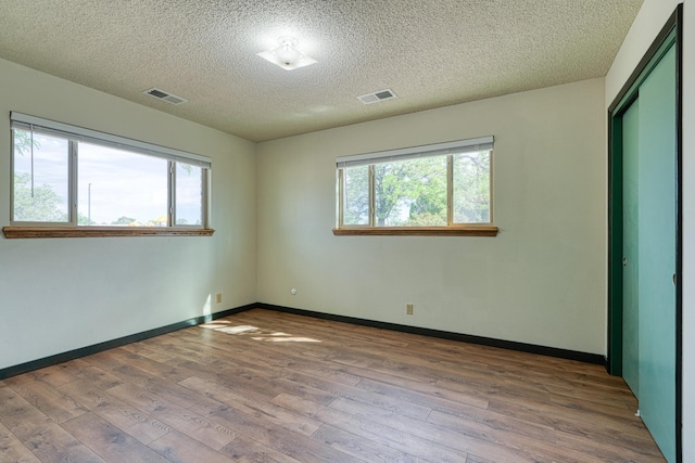 508 Las Marias Dr SE, Rio Rancho, NM 87124 - empty room featuring wood finished floors, healthy amount of natural light, a textured ceiling, and baseboards