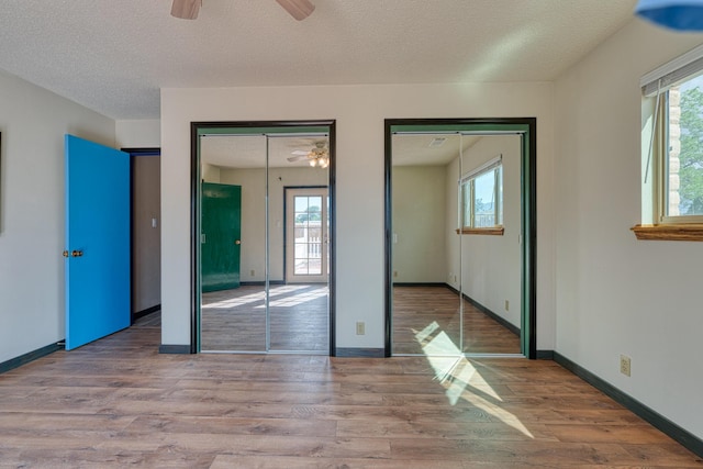 508 Las Marias Dr SE, Rio Rancho, NM 87124 - unfurnished bedroom with multiple closets, wood finished floors, a textured ceiling, and multiple windows