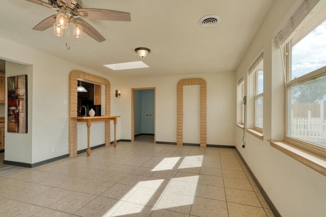 508 Las Marias Dr SE, Rio Rancho, NM 87124 - empty room with light tile patterned floors, a skylight, ceiling fan, and baseboards