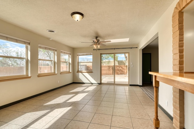 508 Las Marias Dr SE, Rio Rancho, NM 87124 - unfurnished room featuring a ceiling fan, light tile patterned flooring, a textured ceiling, baseboards, and a skylight