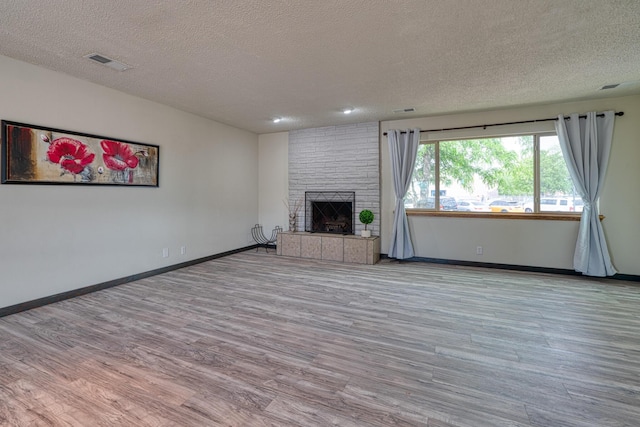 508 Las Marias Dr SE, Rio Rancho, NM 87124 - unfurnished living room featuring a textured ceiling, wood finished floors, a brick fireplace, and baseboards