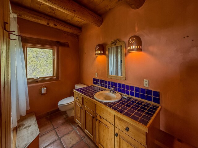 33 Kestrel Rd, Ramah, NM 87321 - bathroom with wooden ceiling, toilet, beamed ceiling, vanity, and tasteful backsplash