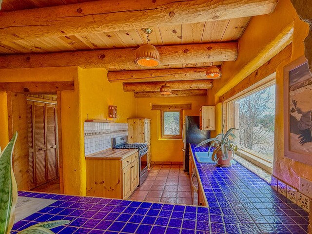 33 Kestrel Rd, Ramah, NM 87321 - kitchen with stainless steel appliances, wooden ceiling, tile counters, beam ceiling, and tile patterned flooring