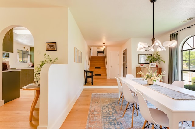 7416 Don Tomas Ln NE, Albuquerque, NM 87109 - dining area with stairway, light wood-style floors, a chandelier, and arched walkways