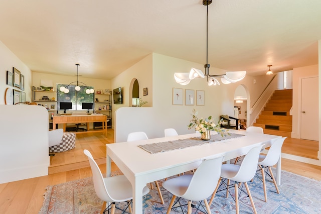 7416 Don Tomas Ln NE, Albuquerque, NM 87109 - dining room featuring stairway, light wood-type flooring, arched walkways, and a chandelier