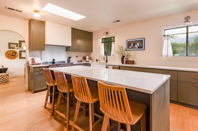 7416 Don Tomas Ln NE, Albuquerque, NM 87109 - kitchen featuring a skylight, light wood-style floors, light countertops, a breakfast bar, and a kitchen island