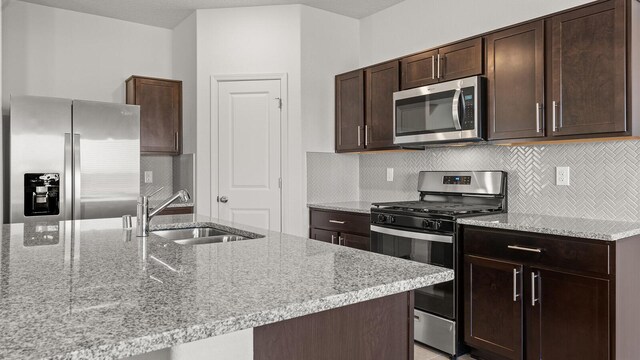 5523 Sagan Loop SE, Albuquerque, NM 87106 - kitchen with stainless steel appliances, a sink, dark brown cabinetry, and tasteful backsplash