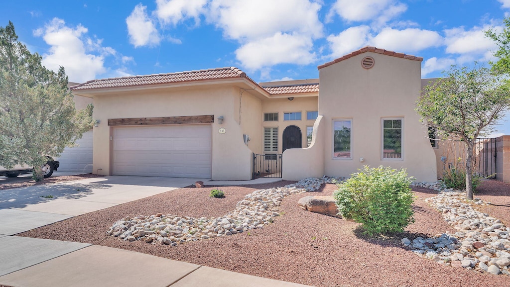 513 Taylor Rd NE, Los Lunas, NM 87031 - mediterranean / spanish home featuring a tile roof, fence, a garage, driveway, and stucco siding