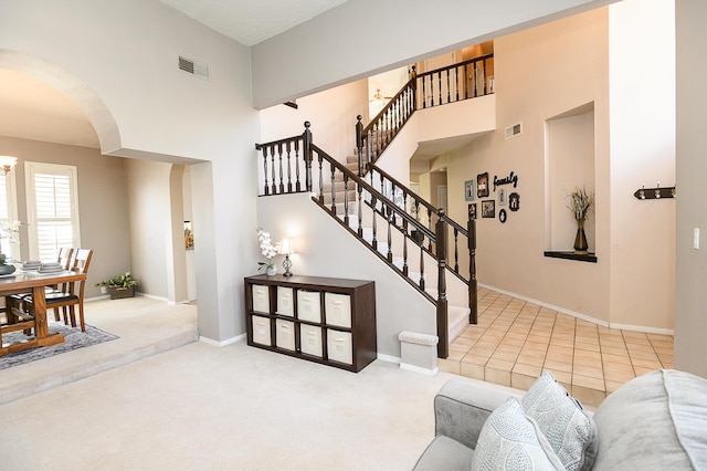 9301 Holm Bursun Dr NW, Albuquerque, NM 87114 - living room featuring arched walkways, a high ceiling, carpet floors, and stairs