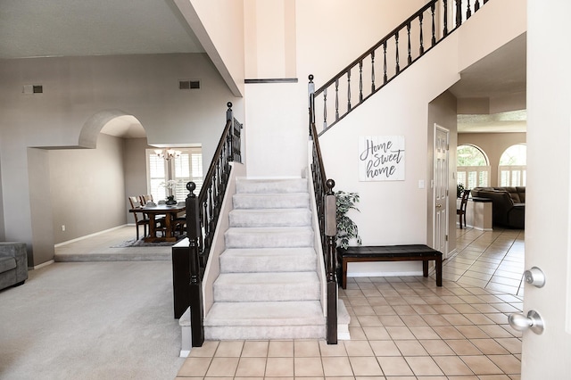 9301 Holm Bursun Dr NW, Albuquerque, NM 87114 - stairs with arched walkways, a towering ceiling, a chandelier, tile patterned flooring, and carpet flooring