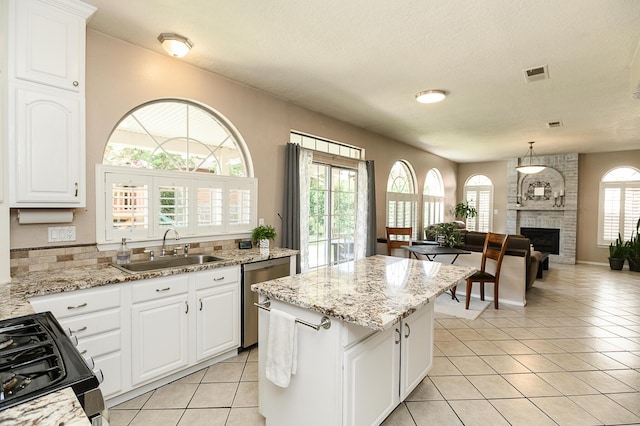 9301 Holm Bursun Dr NW, Albuquerque, NM 87114 - kitchen with black gas range, stainless steel dishwasher, light tile patterned flooring, a kitchen island, and white cabinets