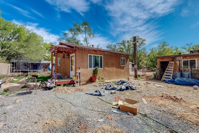 2327 Pajarito Rd SW, Albuquerque, NM 87105 - back of property with a trampoline, stucco siding, and fence