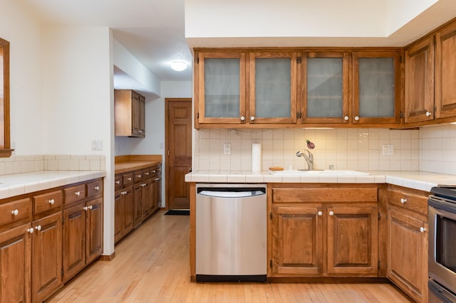 3121 Grande Vista Pl NW, Albuquerque, NM 87120 - kitchen featuring stainless steel appliances, a sink, brown cabinets, light wood finished floors, and decorative backsplash