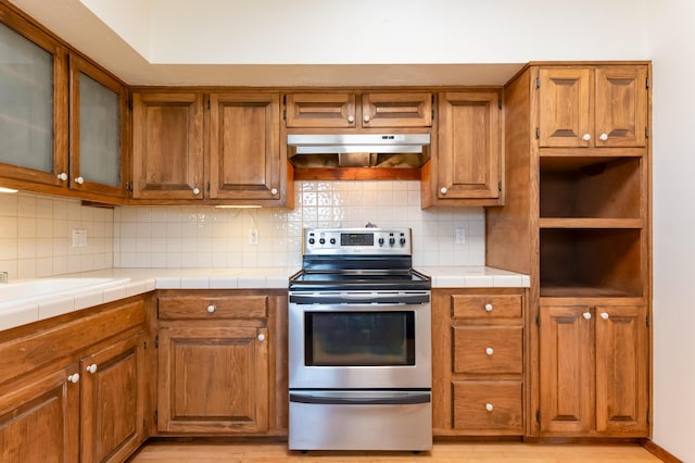 3121 Grande Vista Pl NW, Albuquerque, NM 87120 - kitchen with electric stove, under cabinet range hood, brown cabinets, and backsplash