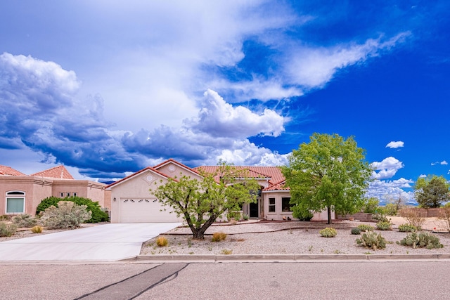 2392 Manzano Loop NE, Rio Rancho, NM 87144 - mediterranean / spanish home featuring an attached garage, a tile roof, driveway, and stucco siding