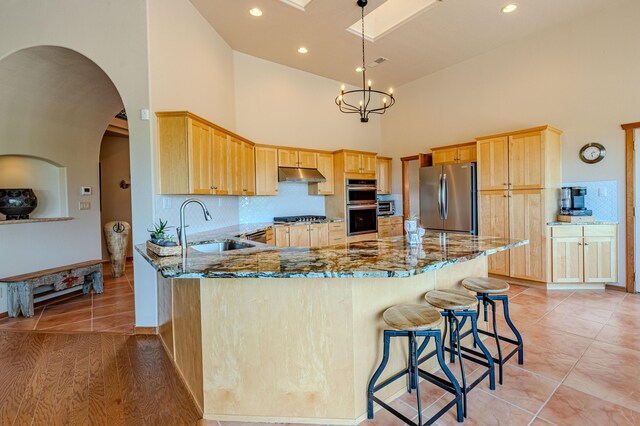 2392 Manzano Loop NE, Rio Rancho, NM 87144 - kitchen with appliances with stainless steel finishes, a sink, high vaulted ceiling, light brown cabinets, and light stone countertops