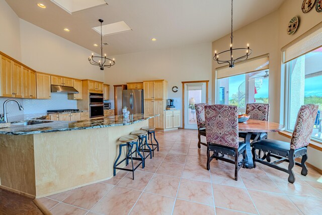 2392 Manzano Loop NE, Rio Rancho, NM 87144 - kitchen with a sink, stainless steel appliances, under cabinet range hood, a chandelier, and a high ceiling