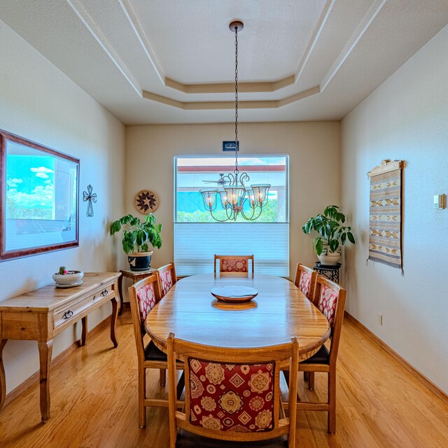 2392 Manzano Loop NE, Rio Rancho, NM 87144 - dining space featuring light wood-style flooring, a tray ceiling, a chandelier, and baseboards