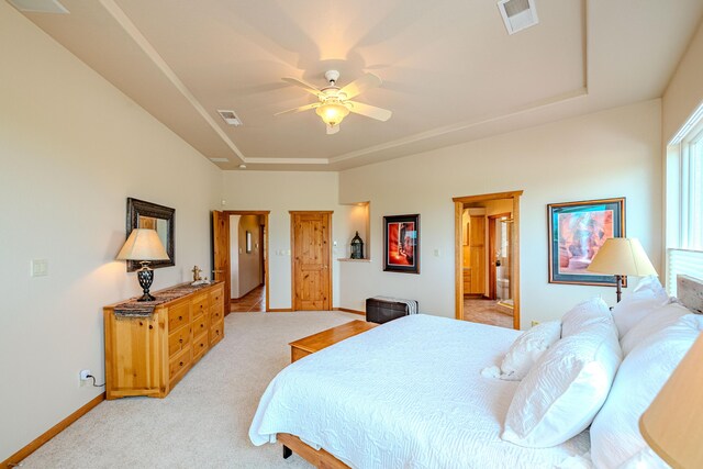 2392 Manzano Loop NE, Rio Rancho, NM 87144 - bedroom featuring light carpet, a tray ceiling, baseboards, ensuite bathroom, and ceiling fan