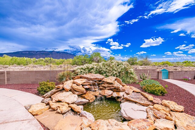 2392 Manzano Loop NE, Rio Rancho, NM 87144 - view of yard with fence, a mountain view, and a small pond