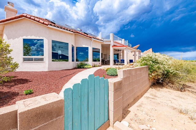 2392 Manzano Loop NE, Rio Rancho, NM 87144 - view of front of home with a gate, a fenced front yard, roof mounted solar panels, a chimney, and stucco siding