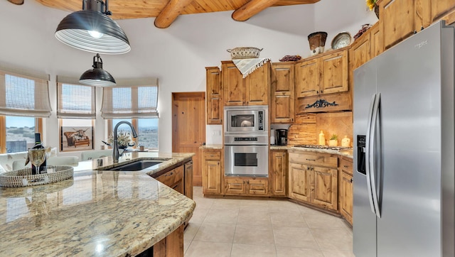 59 Sky Mountain Rd, Placitas, NM 87043 - kitchen with stainless steel appliances, a sink, brown cabinets, tasteful backsplash, and beamed ceiling