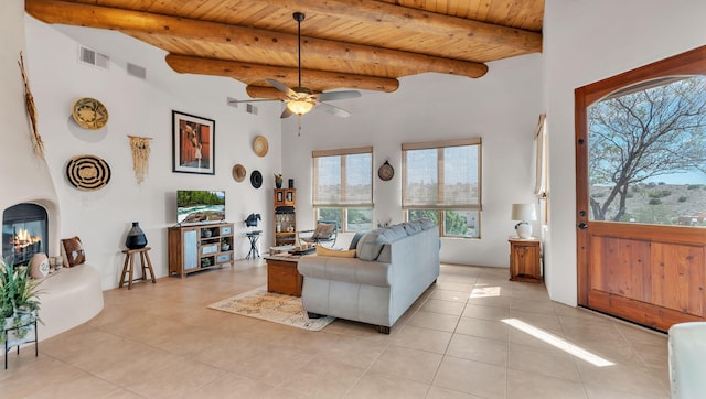 59 Sky Mountain Rd, Placitas, NM 87043 - living room featuring a large fireplace, a ceiling fan, wood ceiling, light tile patterned floors, and a towering ceiling