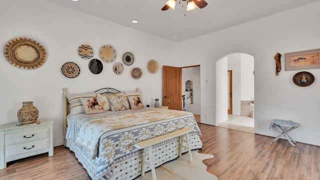 59 Sky Mountain Rd, Placitas, NM 87043 - bedroom featuring arched walkways, light wood-type flooring, ceiling fan, and ensuite bathroom