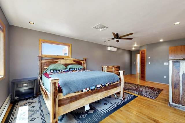 52 Tejon Canon Rd, Placitas, NM 87043 - bedroom featuring a baseboard heating unit, wood finished floors, a wood stove, recessed lighting, and ceiling fan