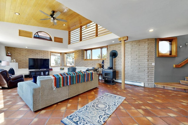 52 Tejon Canon Rd, Placitas, NM 87043 - tiled living room with a wood stove, a baseboard heating unit, a ceiling fan, recessed lighting, and brick wall