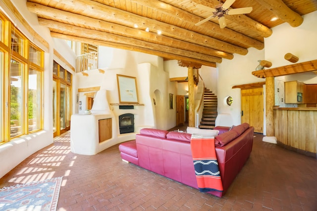 59 Perdiz Canyon Rd, Placitas, NM 87043 - living area featuring wooden ceiling with exposed beams, brick floors, stairway, a fireplace with raised hearth, and ceiling fan
