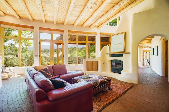 59 Perdiz Canyon Rd, Placitas, NM 87043 - living room featuring wooden ceiling with exposed beams, brick floors, arched walkways, and a large fireplace