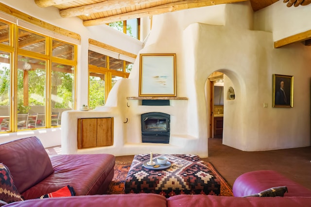 59 Perdiz Canyon Rd, Placitas, NM 87043 - living area with arched walkways, wooden ceiling with exposed beams, wood finished floors, and a glass covered fireplace