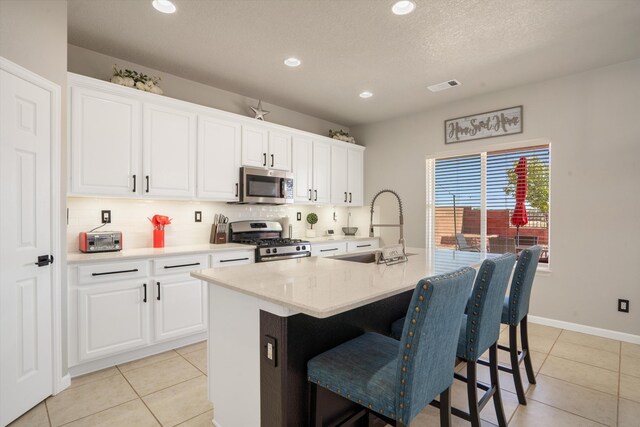 3604 Plano Vista Rd NE, Rio Rancho, NM 87124 - kitchen featuring stainless steel appliances, a breakfast bar, backsplash, a center island with sink, and light tile patterned floors