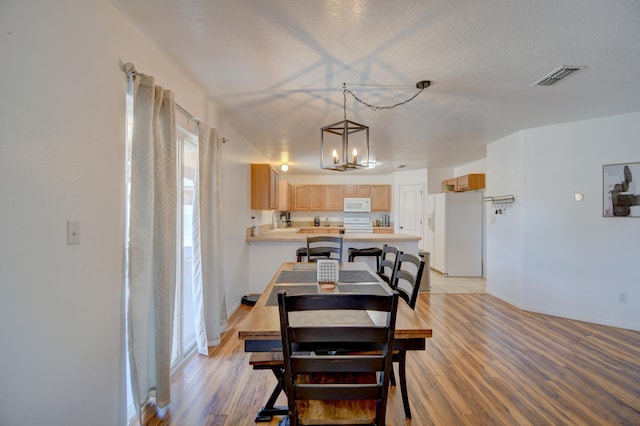 dining space with a chandelier, light wood-style floors, and baseboards